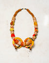 YELLOW, RED AND BROWN JACARANDA WOOD AND PLASTIC BEADS IN CHITENGE MATERIAL NECKLACE , PAIRED WITH EARRINGS AND AN AFRICAN MAIDEN PRINTED WRAPPER