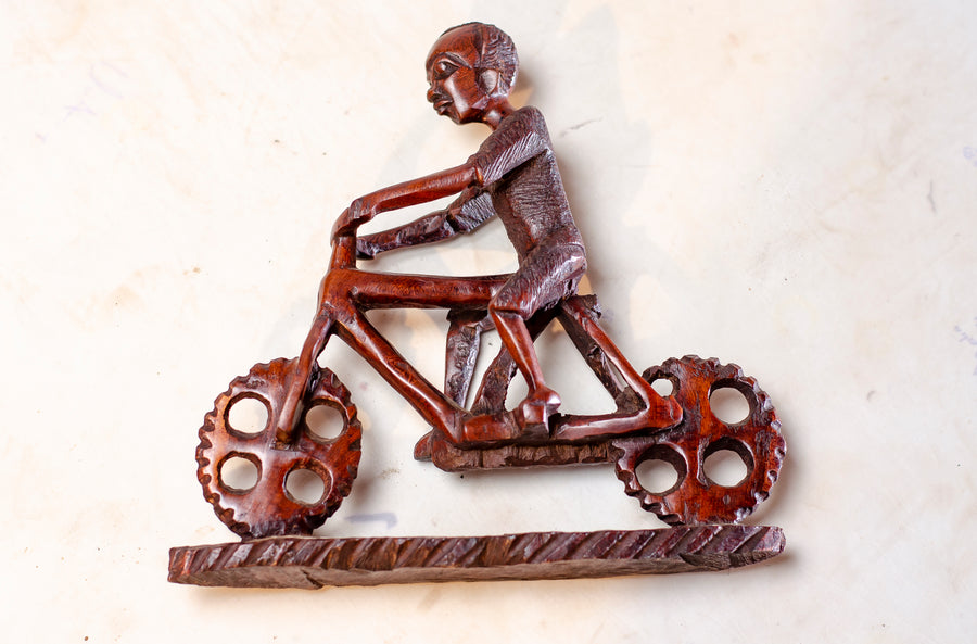 MAN RIDING A BICYCLE MADE OUT OF IRON WOOD